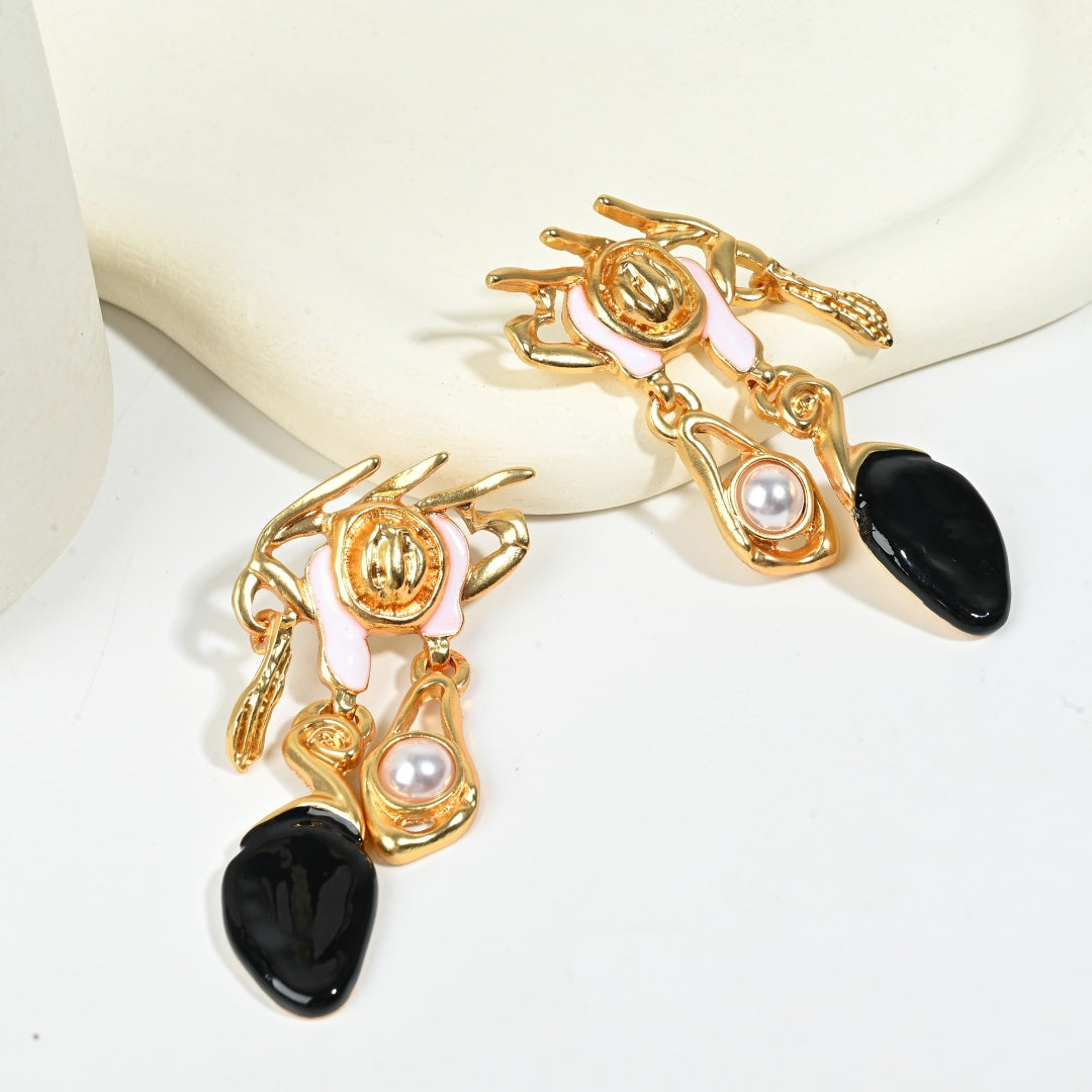 Baroque asymmetric earring detail highlighting crown design, black resin teardrop and gold plated texture