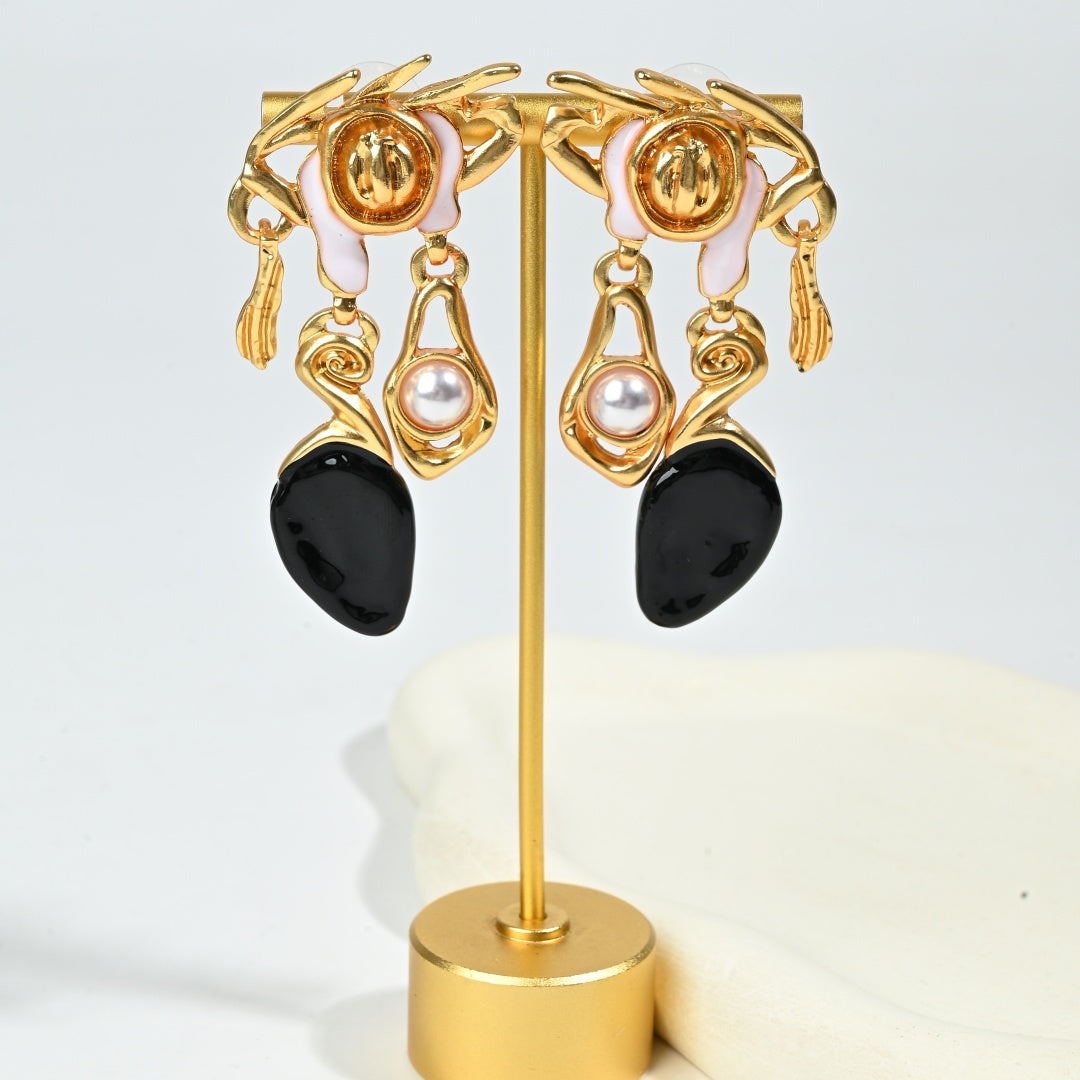 Detail shot of asymmetric resin drop earring with baroque gold crown motif and dark resin embellishment