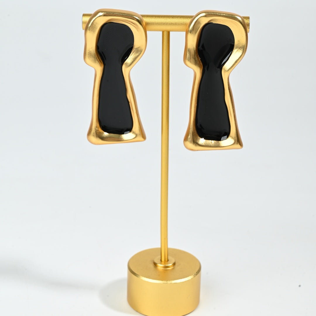 Styled detail shot of Secret Keyhole earring showing black enamel keyhole motif and gold plated brass setting