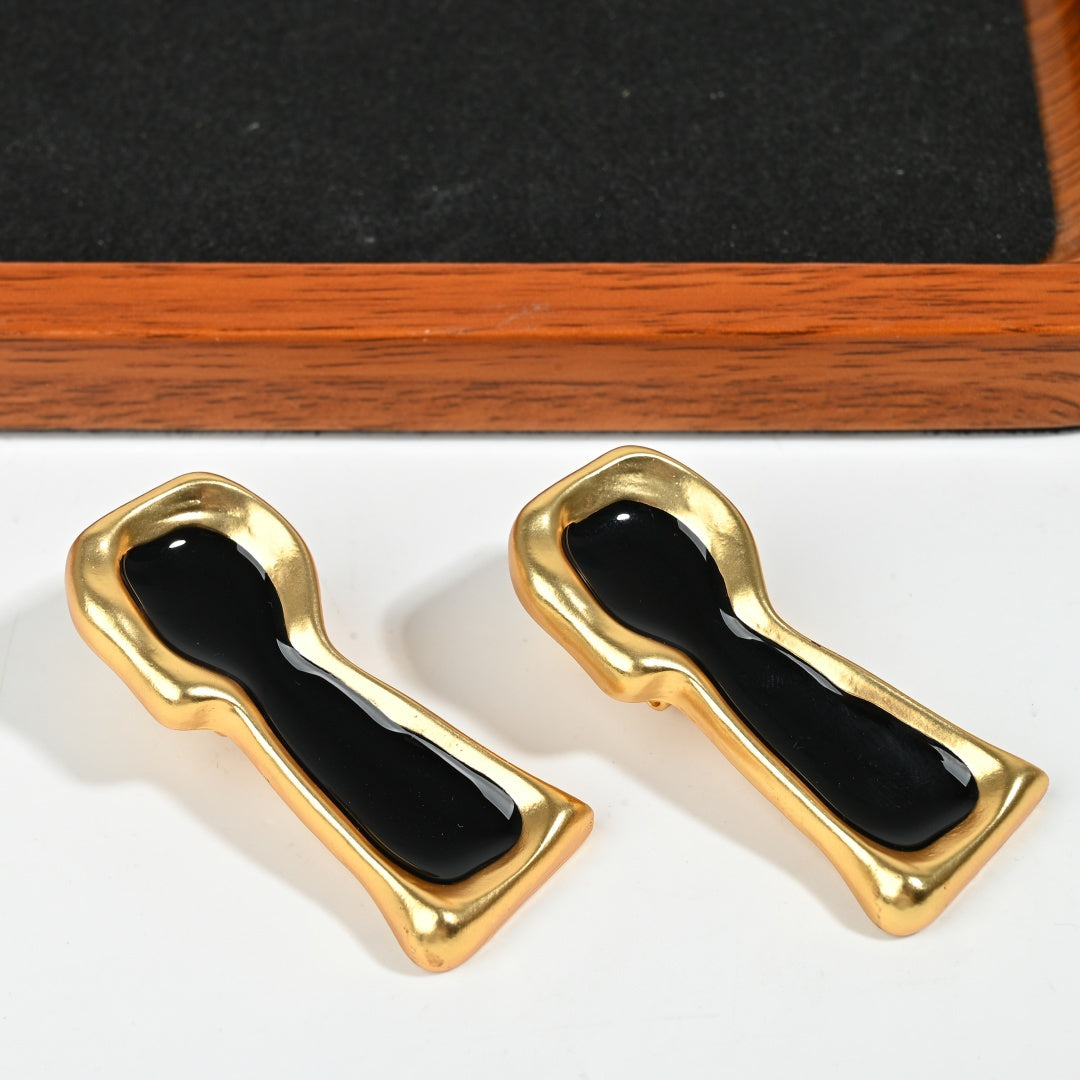 Close-up of surrealist keyhole drop earring with black enamel inlay and intricate 18K gold plated detailing


