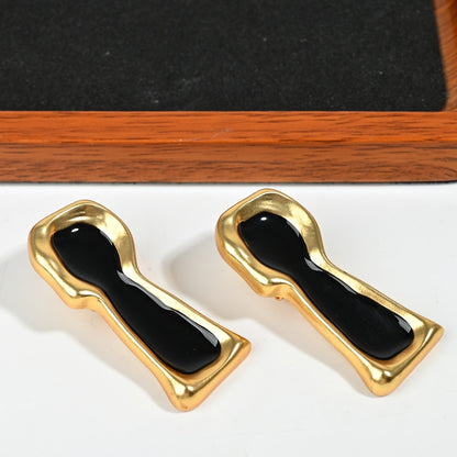 Close-up of surrealist keyhole drop earring with black enamel inlay and intricate 18K gold plated detailing

