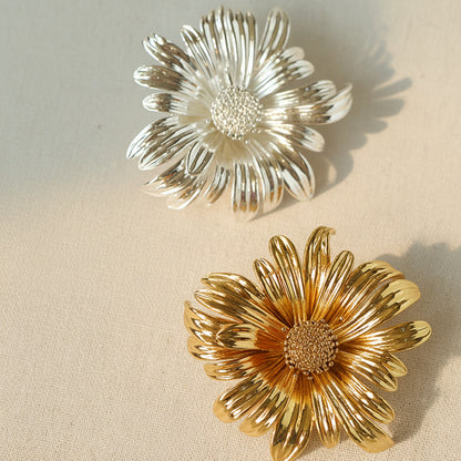 Pair of oversized vintage-style metal flower brooches in textured silver and antique gold finishes, featuring intricate layered petals and a detailed seed center.