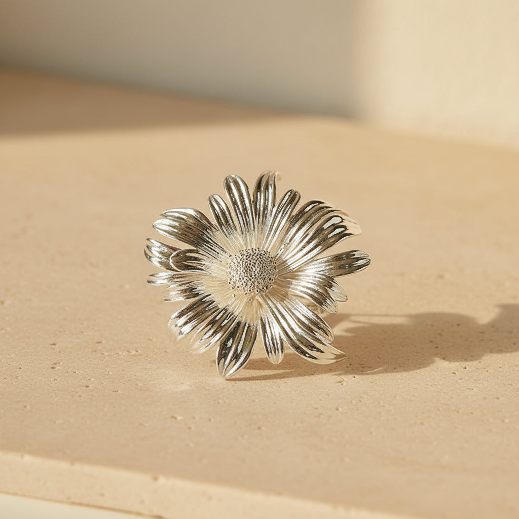 Side view of a silver metallic sun-ray flower brooch on a neutral background, highlighting the depth and elegant curvature of the petals.