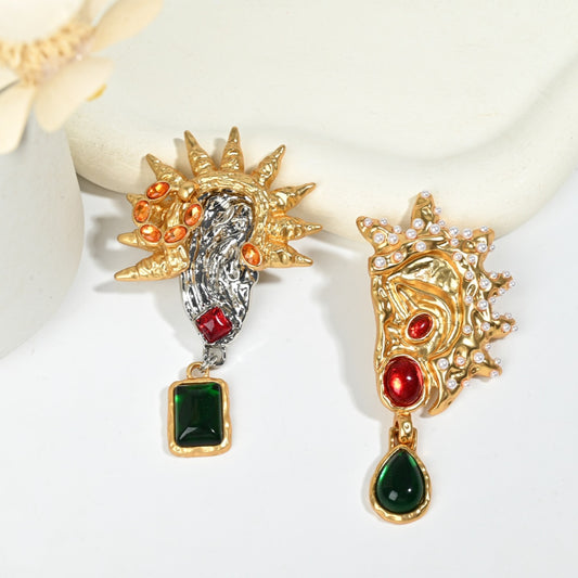 Close-up detail of surrealist asymmetric earring showing sunburst motif with crystal accents and gold texture