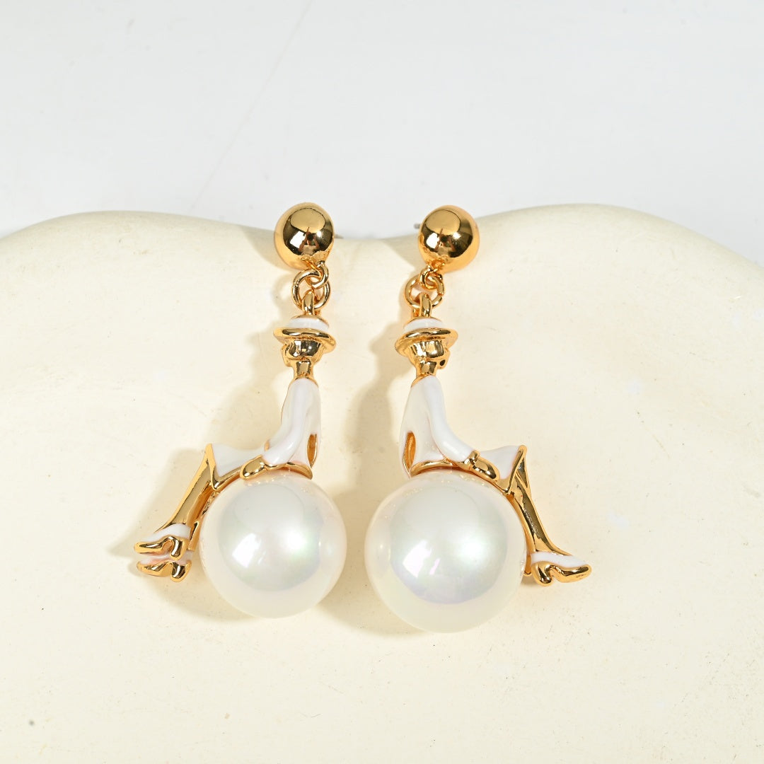 Close-up detail of ballerina figural earring with pearl drop, vintage whimsical gold jewelry styled shot