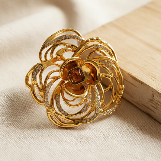 Detailed filigree gold camellia pin showing premium craftsmanship and texture.