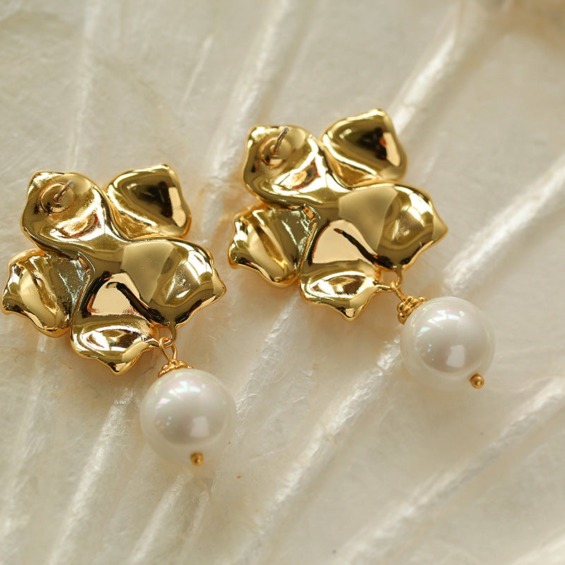 Close-up detail of detailed gold metalwork on floral pearl earrings.