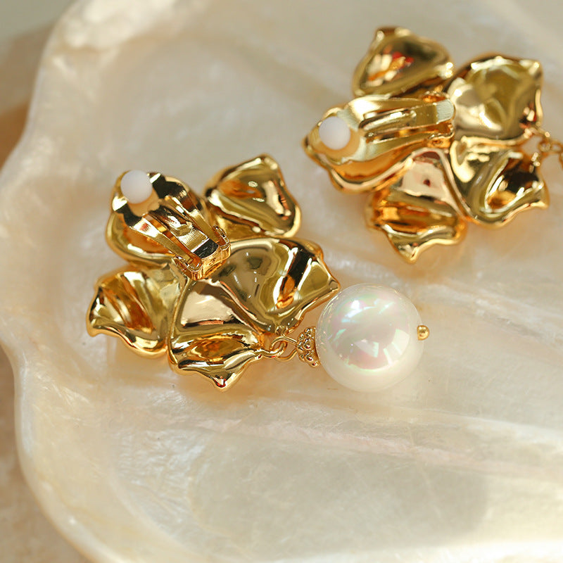 Top view of model wearing intricate gold floral and pearl stud earrings.