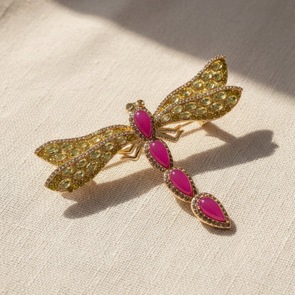 Side profile view of the Gilded Libellule Statement Brooch, showcasing the unique organic anatomy of the brass body and the exquisite detail of the jeweled fuchsia and yellow wings.
