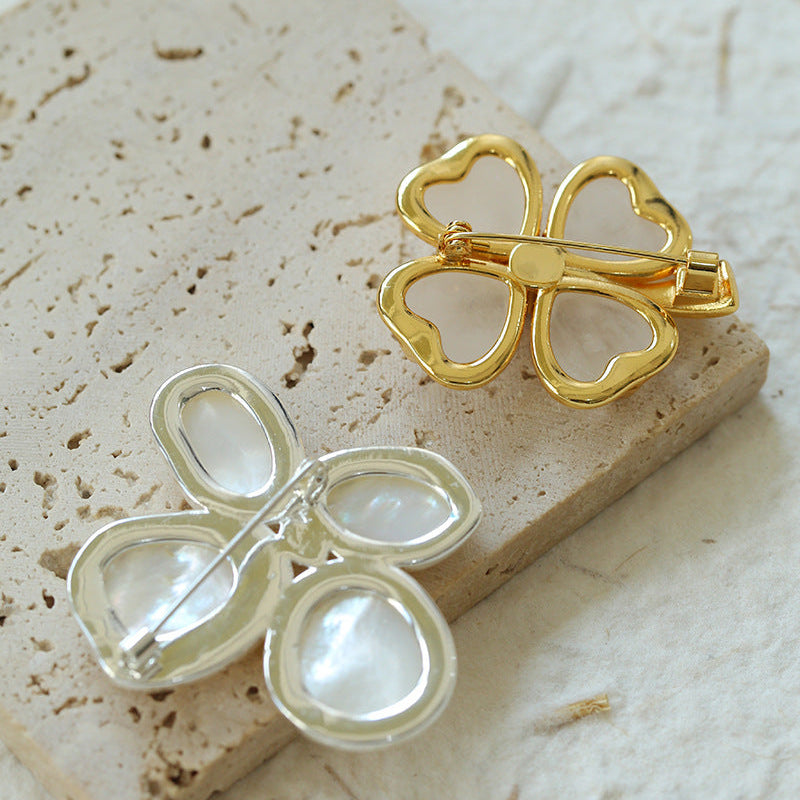Comparison of the gold and silver-trimmed flower brooches, with one showing the sturdy back pin mechanism and the polished finish of the jewelry.