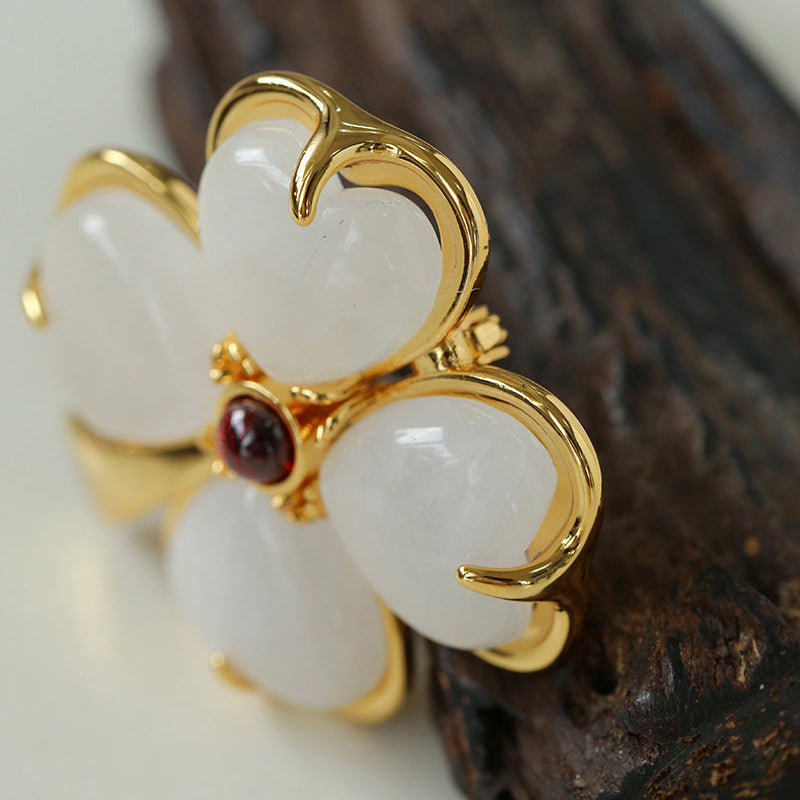 Angled close-up of the sculptural floral brooch, emphasizing the 3D layered design and the smooth, rounded texture of the white stone petals.