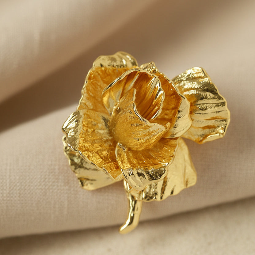 Detail of sculptural gold flower pin showing molten metal texture.
