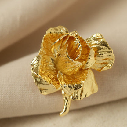 Detail of sculptural gold flower pin showing molten metal texture.