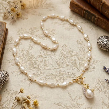 Flat lay of the key pendant pearl necklace on a vintage setting with old books, emphasizing a classic "storytelling" aesthetic.
