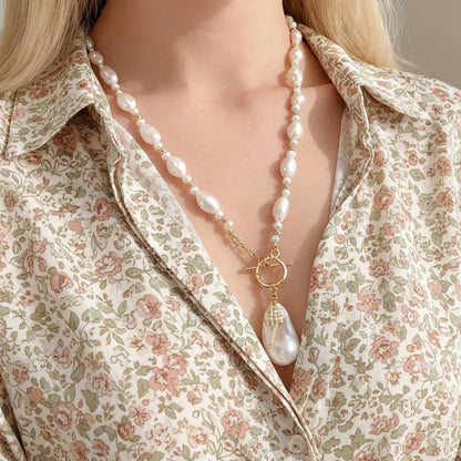 Lifestyle shot of a model wearing the baroque pearl key necklace, demonstrating how the symbolic key pendant adds a focal point to the outfit.