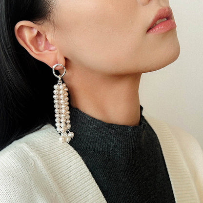 Side profile of a model wearing the long pearl waterfall earrings, demonstrating the movement and elegant length of the jewelry against a casual outfit.