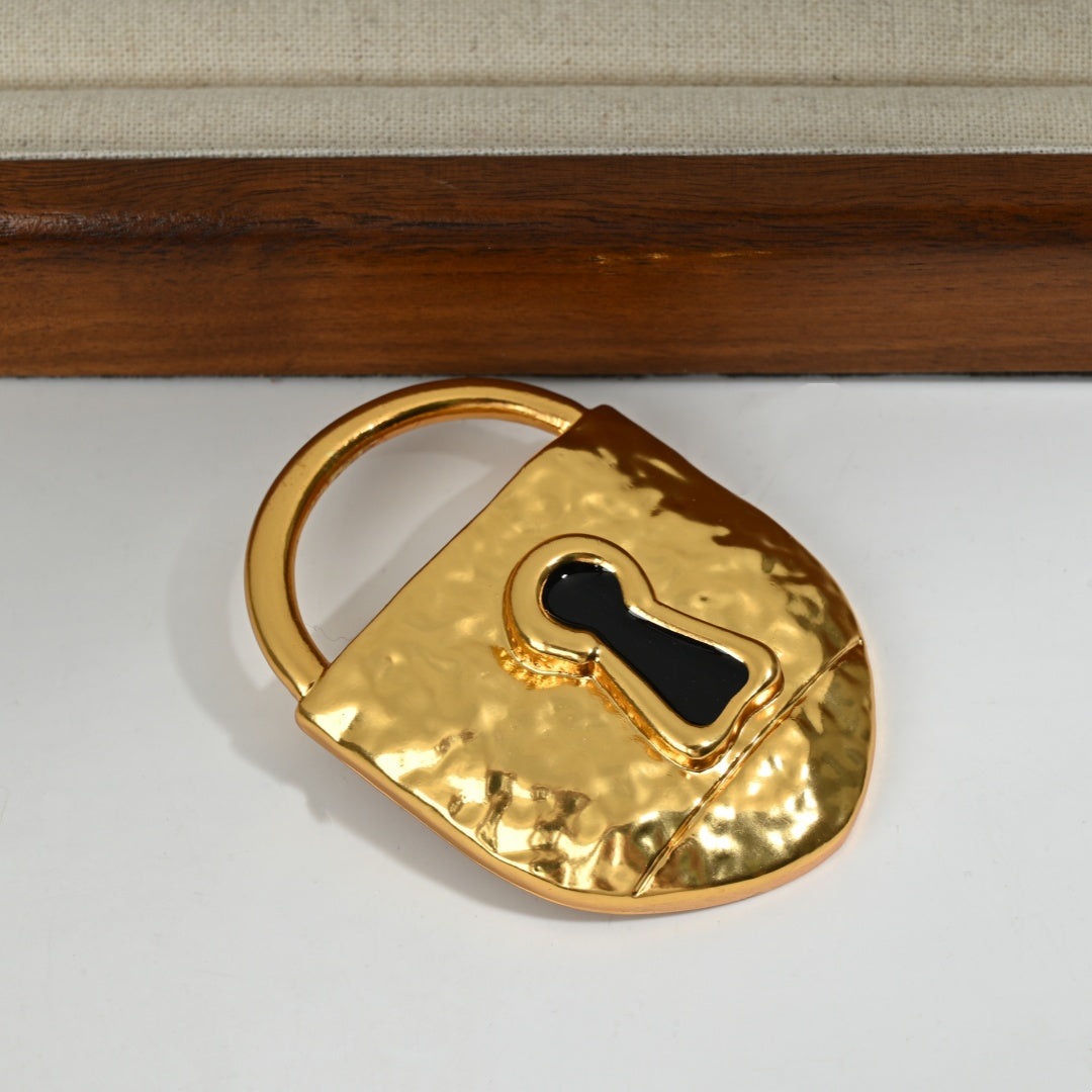 Styled detail shot of 18K gold plated lock brooch with surrealist design, luxury brass statement jewelry

