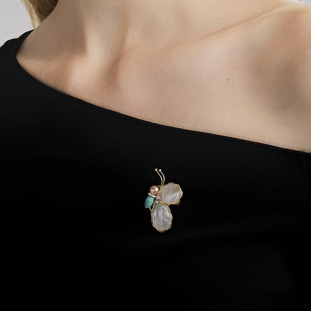 Elegant Woman Wearing a Butterfly Mother of Pearl Brooch on an Off-the-shoulder Black Dress