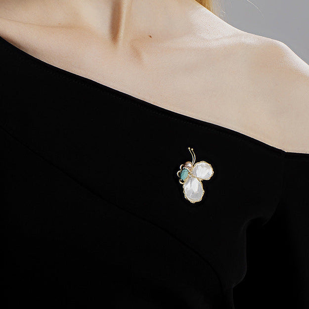 Elegant Woman Wearing a Butterfly Mother of Pearl Brooch on an Off-the-shoulder Black Dress.