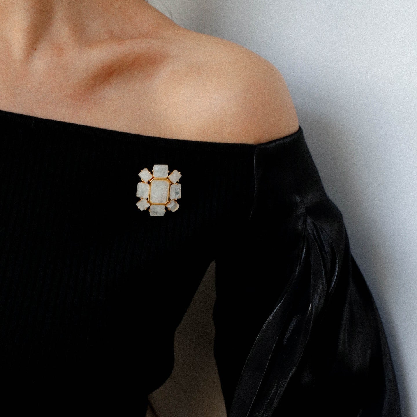 Elegant crystal brooch worn on a black off-the-shoulder evening dress, sophisticated statement jewelry for gala or wedding.