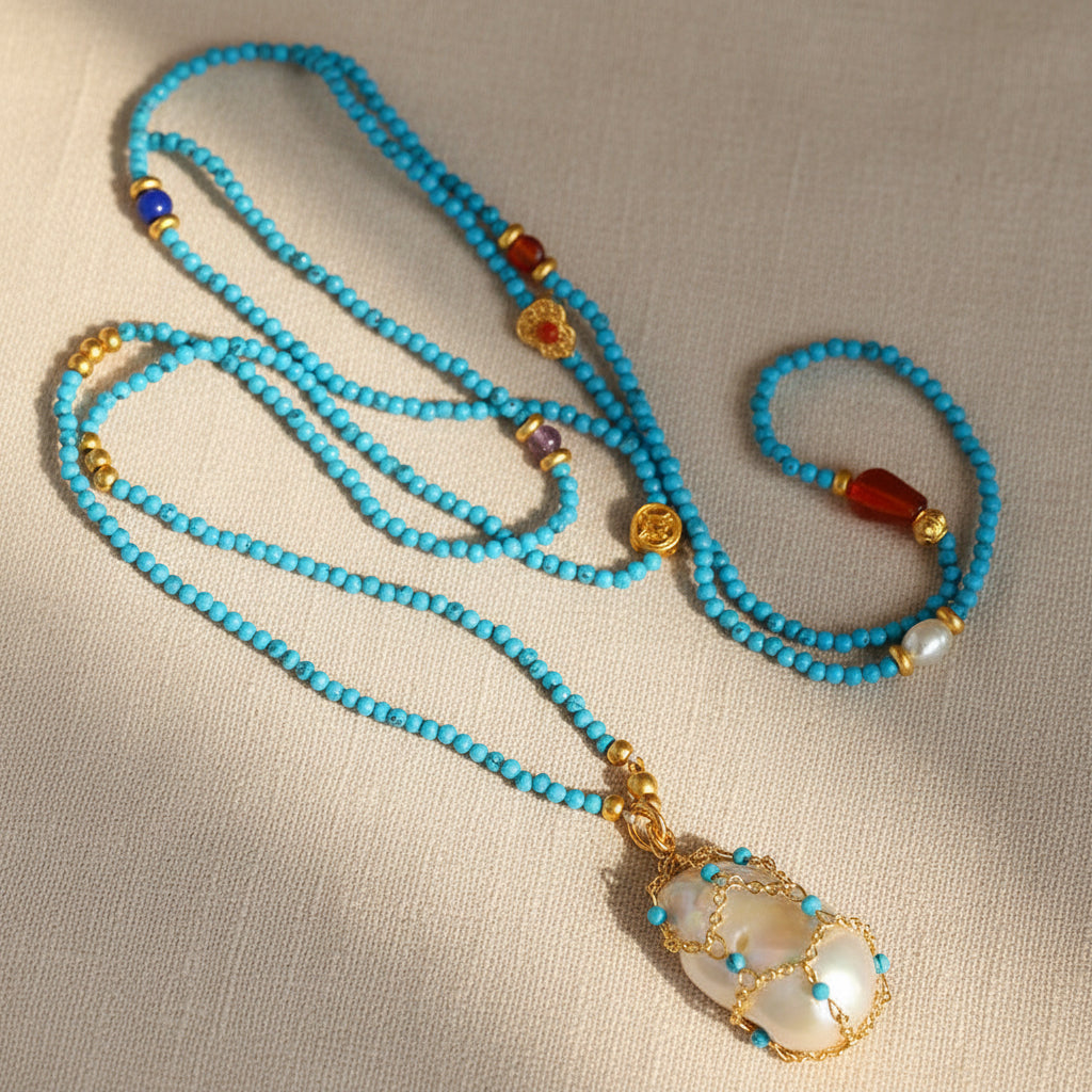Artisan-wrapped baroque pearl and stabilized turquoise beaded necklace on beige background 18K gold plated brass

