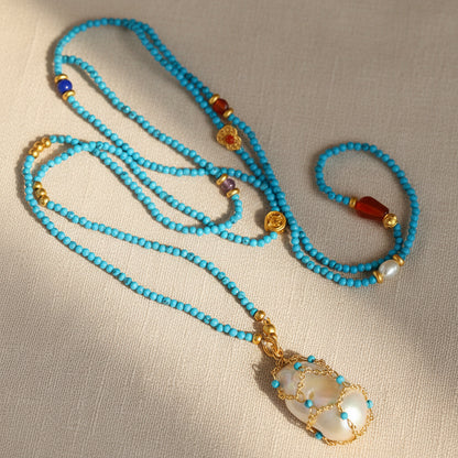 Artisan-wrapped baroque pearl and stabilized turquoise beaded necklace on beige background 18K gold plated brass

