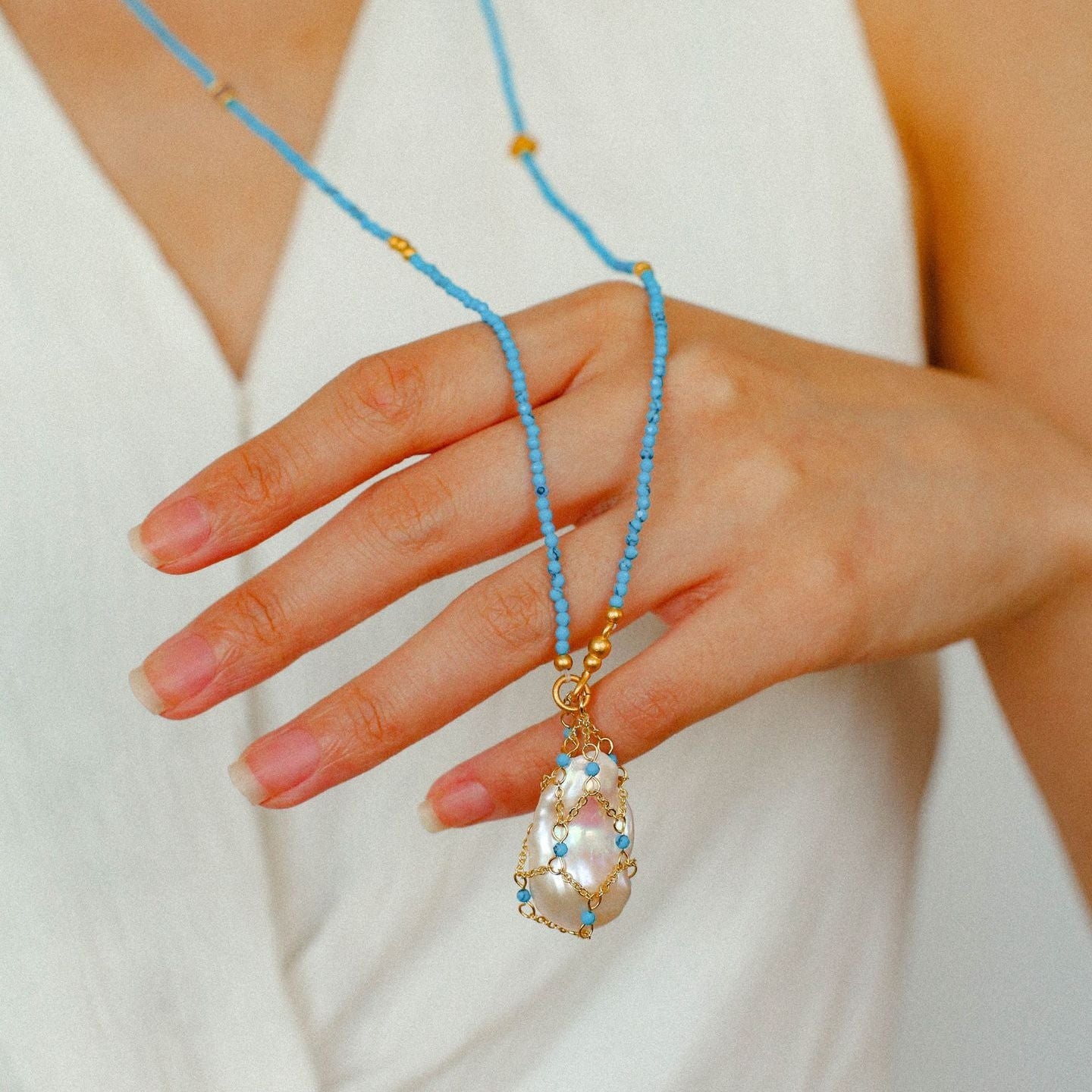 Close-up detail of artisan-wrapped baroque pearl and turquoise beaded necklace 18K gold plated brass texture

