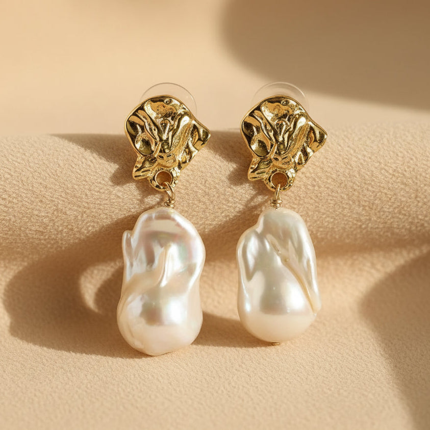 Detail shot of hand-sculpted molten gold baroque pearl earrings on beige fabric background surrealist jewelry

