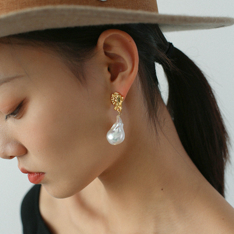 Model side profile wearing baroque pearl drop earrings 18K gold plated lava statement earrings surrealist style


