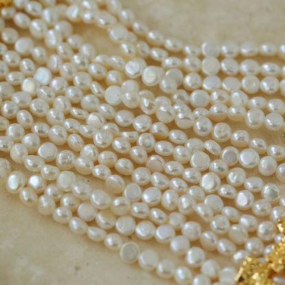 Close-up detail of multi-strand mini freshwater pearl choker on beige background 18K gold plated brass clasp and pearl texture

